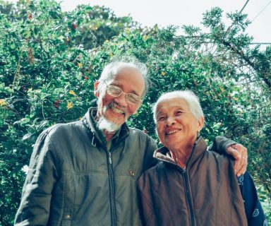 An older couple standing together, smiling.