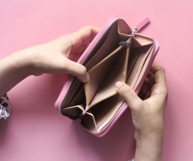 Two hands holding a pink wallet open; it's empty.