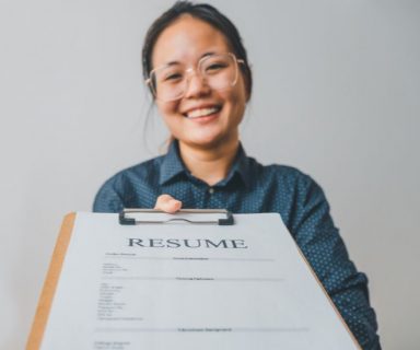 A woman holding a clipboard with a resume on it.