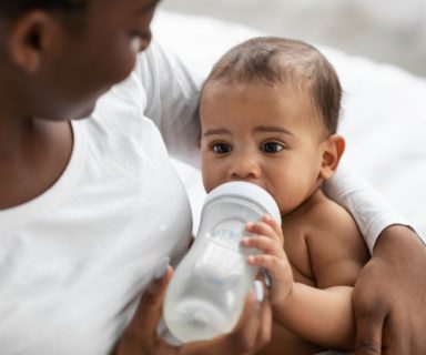A mother feeding their baby from a bottle