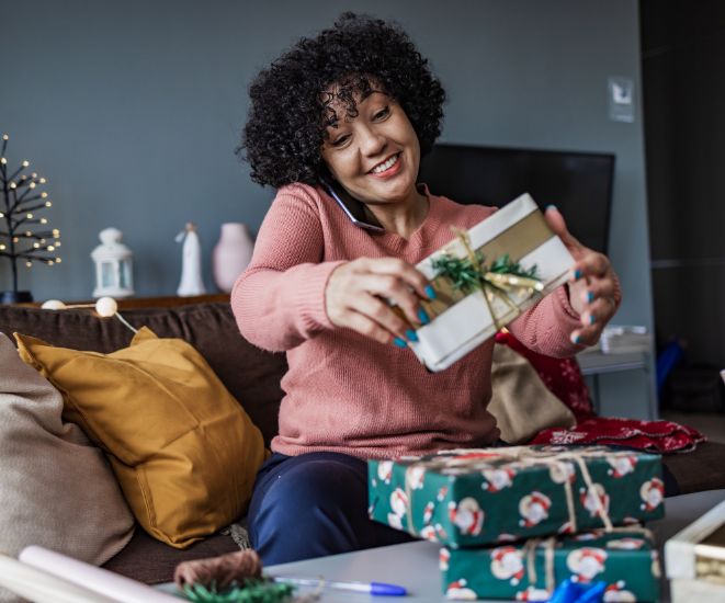 A woman wrapping presents while talking on the phone.