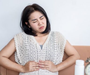 A woman holding her hands on her stomach as if in pain.