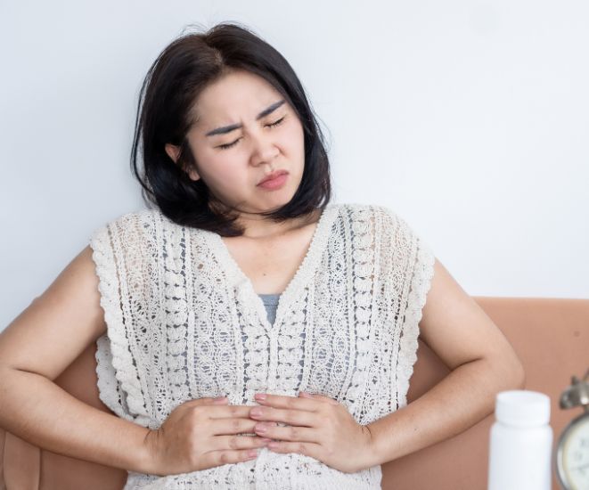 A woman holding her hands on her stomach as if in pain.